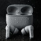 Black and white photo of noise cancelling earbuds with charging case on dark background